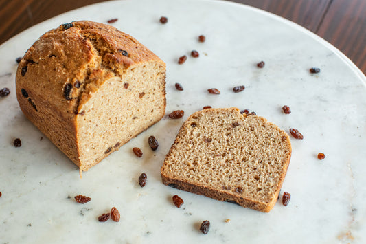 Sliced gluten-free cinnamon raisin sourdough bread sliced on a marble display with raisins scattered around